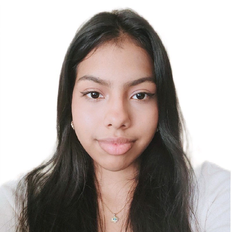 Headshot of Amanda, a multiracial Venezuelan woman with long black hair and a cream-colored top looking at the camera in front of a white background