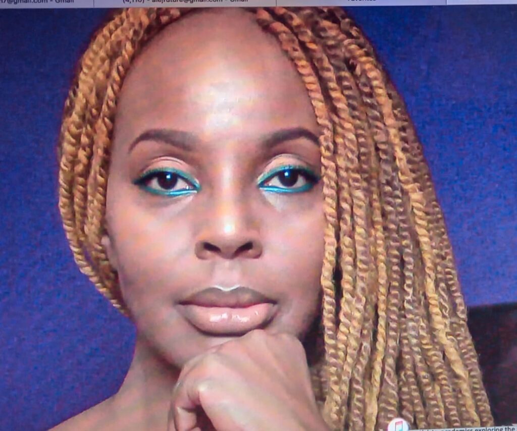 Headshot of Esther A. Armah, a global Black chick with aqua blue eye makeup and long bronze twists