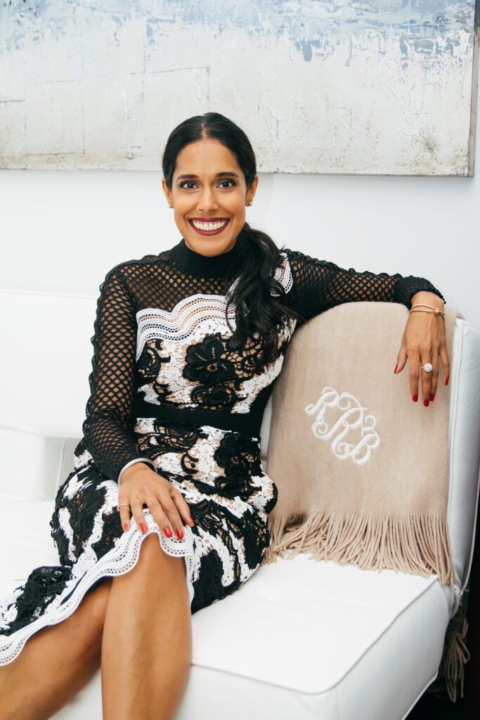 Headshot of Ritu Bhasin, a Punjabi Indian-Canadian woman with long, black hair and a black and white floral dress.