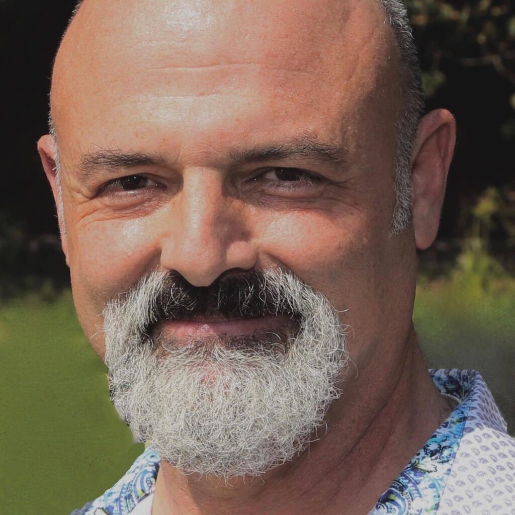 Headshot of Jared Seide, a White cis male with salt and pepper facial hair wearing a patterned blue and white button-down.